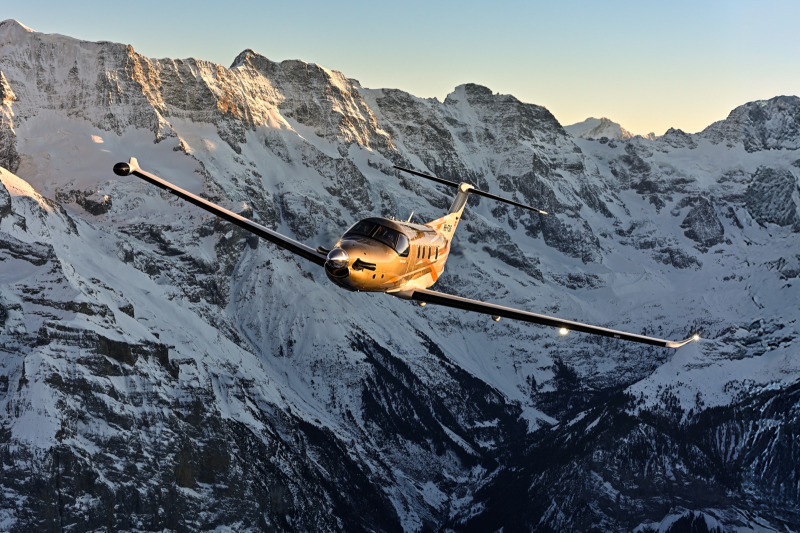 Pilatus PC-12 in flight above the snow-covered Swiss Alps at golden hour