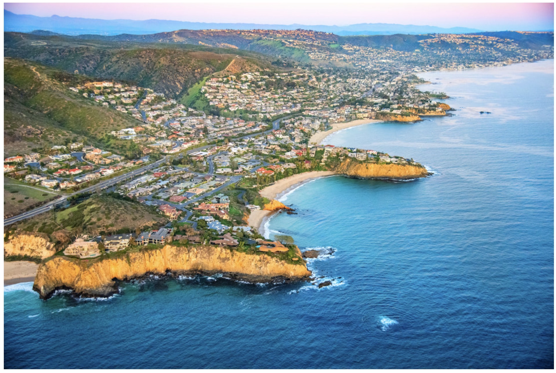 Aerial view of an Orange County coastal headland with cliffs meeting the Pacific Ocean